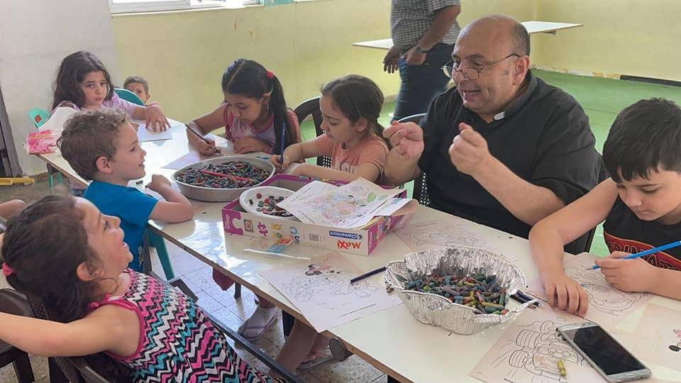 Padre Gabriel Romanelli e as crianças de sua paróquia durante bombardeio na Faixa de Gaza